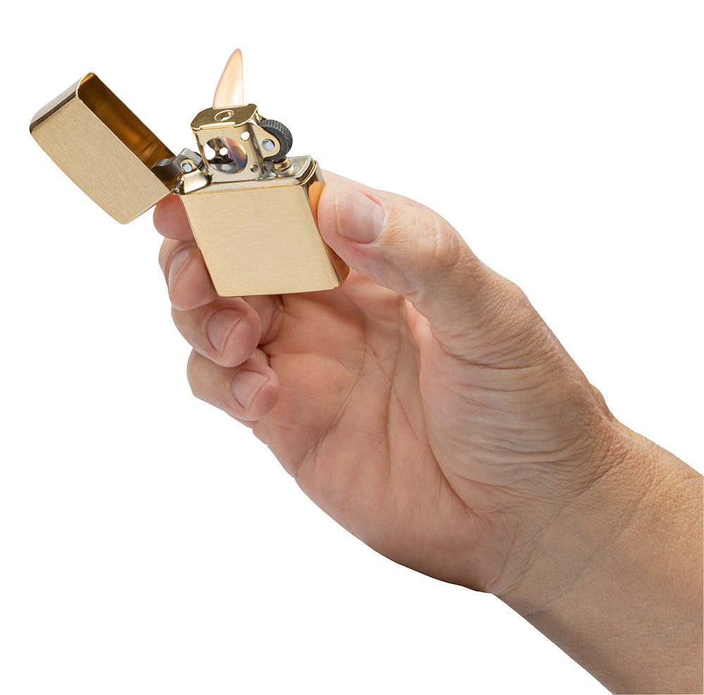 Eine Hand hält ein geöffnetes, brennendes goldfarbenes Zippo-Feuerzeug, bereit zum Anzünden, vor einem weißen Hintergrund.
