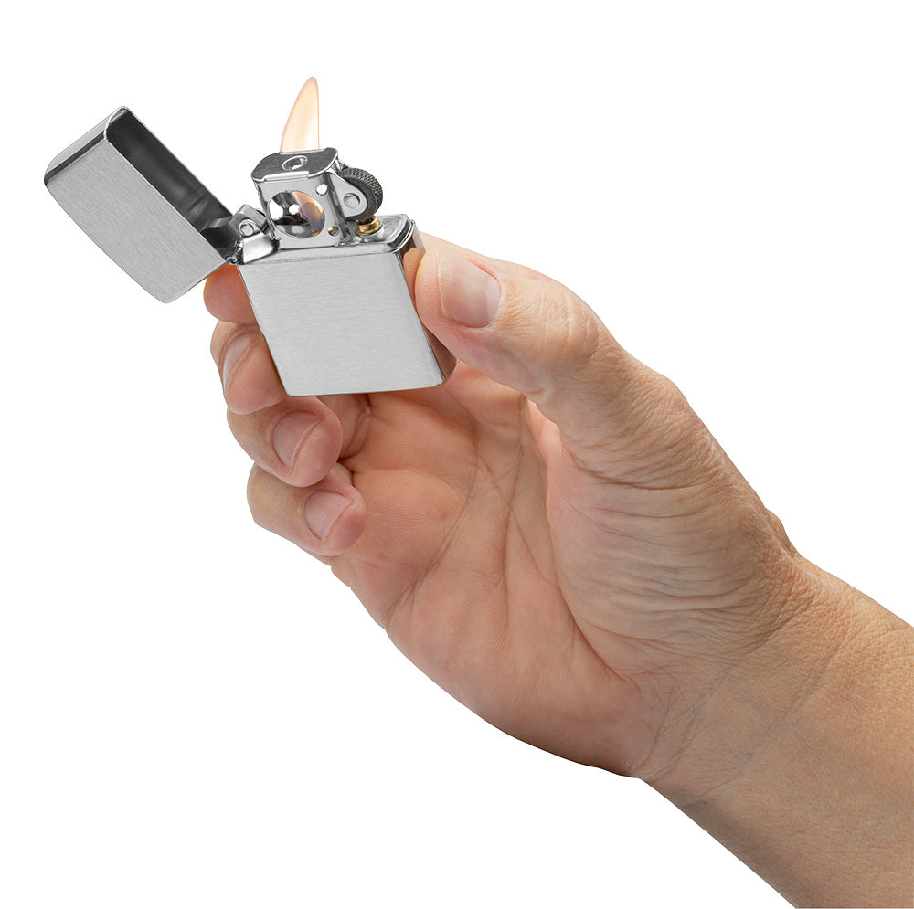 Eine Hand hält ein geöffnetes, silbernes Zippo-Feuerzeug, das eine Flamme erzeugt, in einem neutralen, weißen Hintergrund.