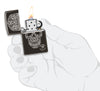 Zippo Feuerzeug Frontansicht Hochglanz schwarz geöffnet und angezündet mit eingraviertem Totenschädel aus Schnörkeln designt von Anne Stokes in stilisierter Hand